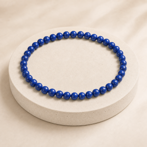 Clasp-free royal blue lapis lazuli round bead necklace on an ivory stone display